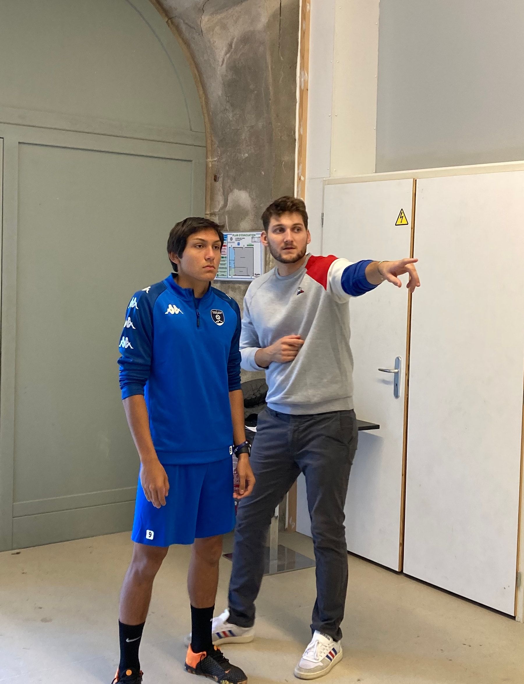 Dans une salle d'entraînement, Baptiste Marmoud guide un jeune sportif en lui indiquant une direction du bras.
