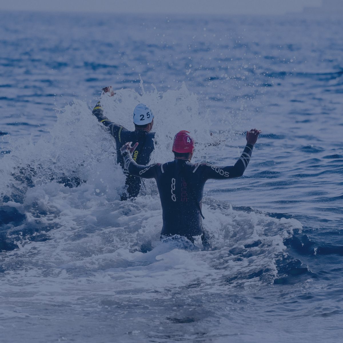 Deux concurrents en combinaison entrent dans l'eau au départ d'une épreuve.
